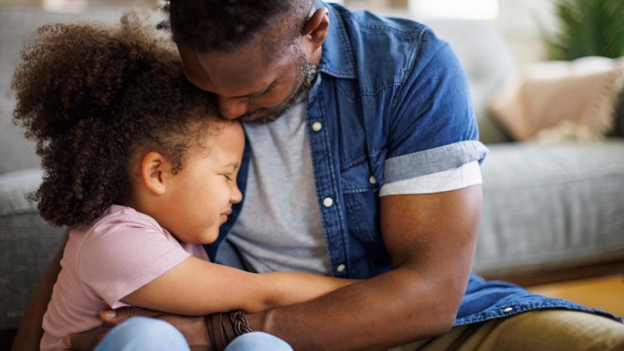 
		Father holds his little daughter tightly in his arms
	